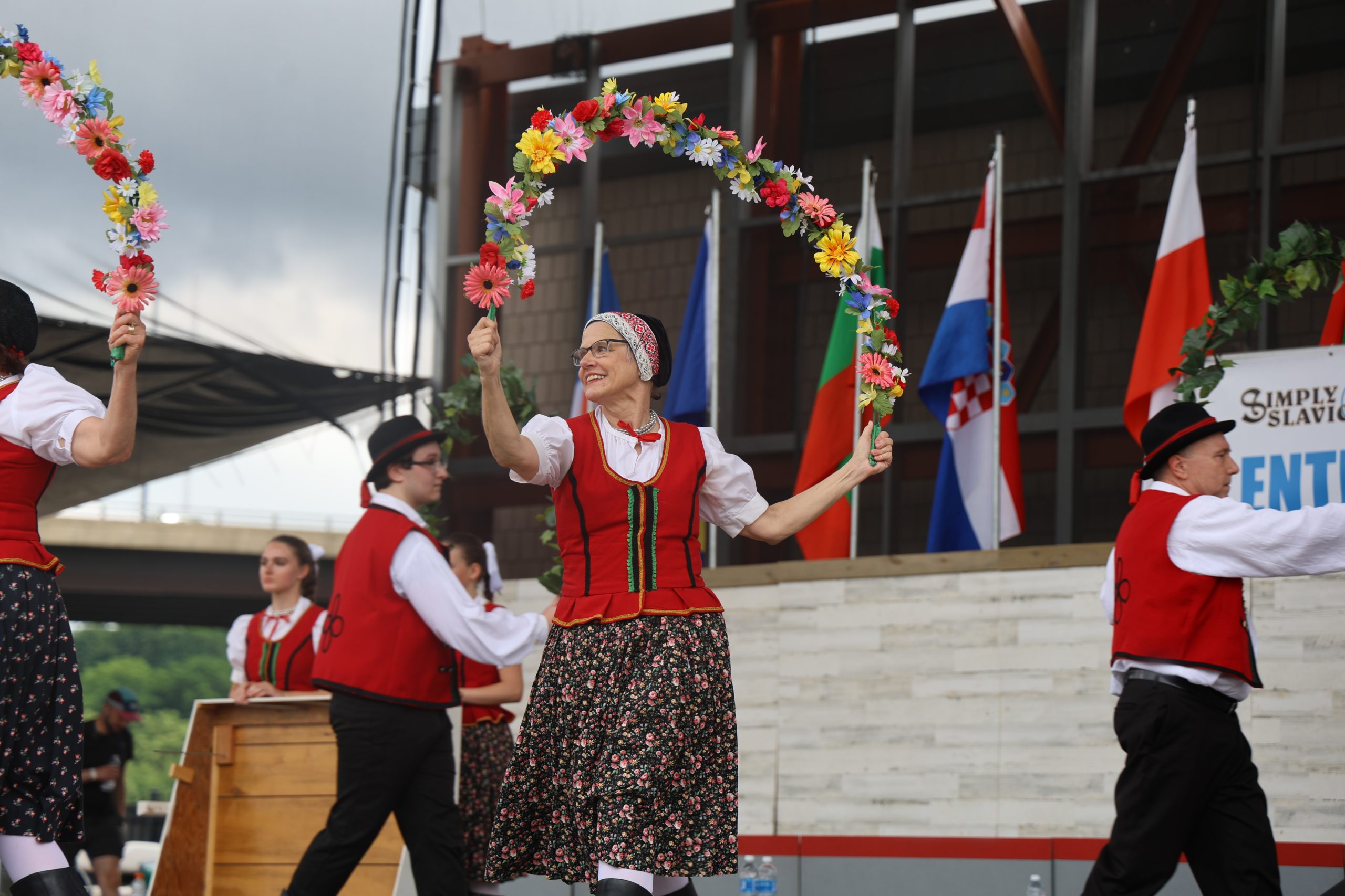 People in slavic clothes holding an arch of flowers during a performance