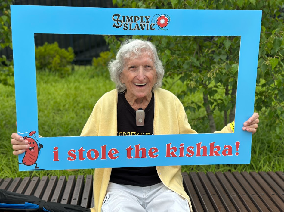 Smiling lady holding a simply slavic frame that says "I stole the kishka"